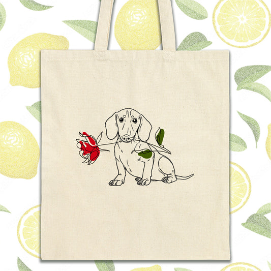 a dog with a rose in its mouth on a tote bag