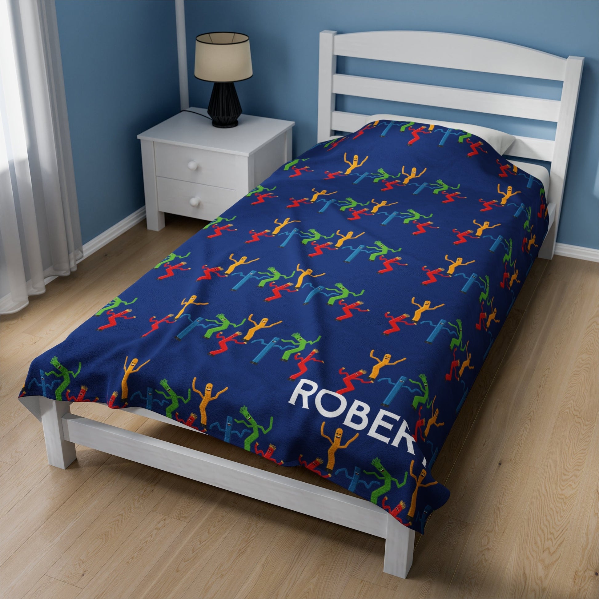 a bed with a blue bedspread with colorful people on it